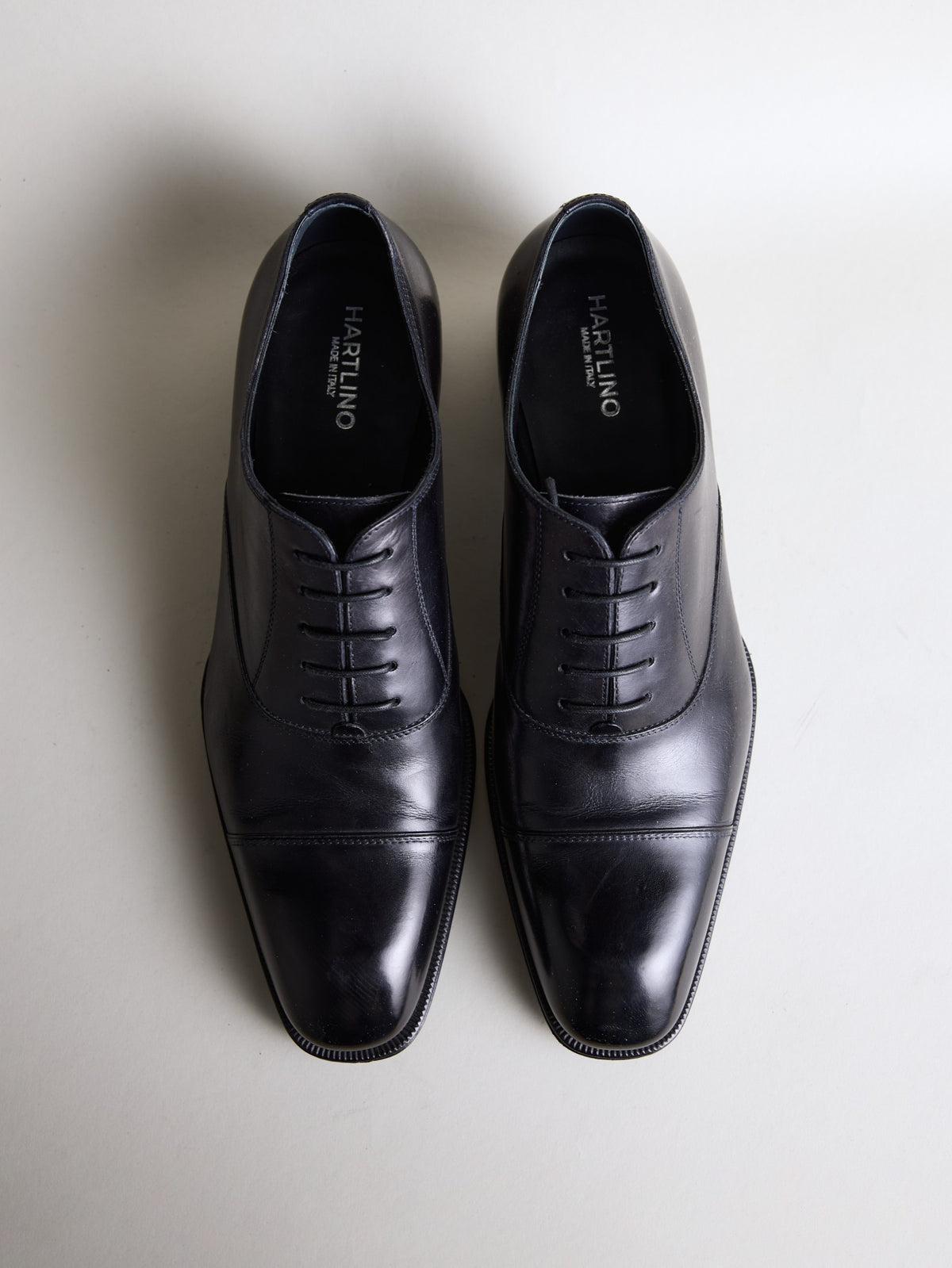 Pair of black cap-toe oxford shoes seen from above