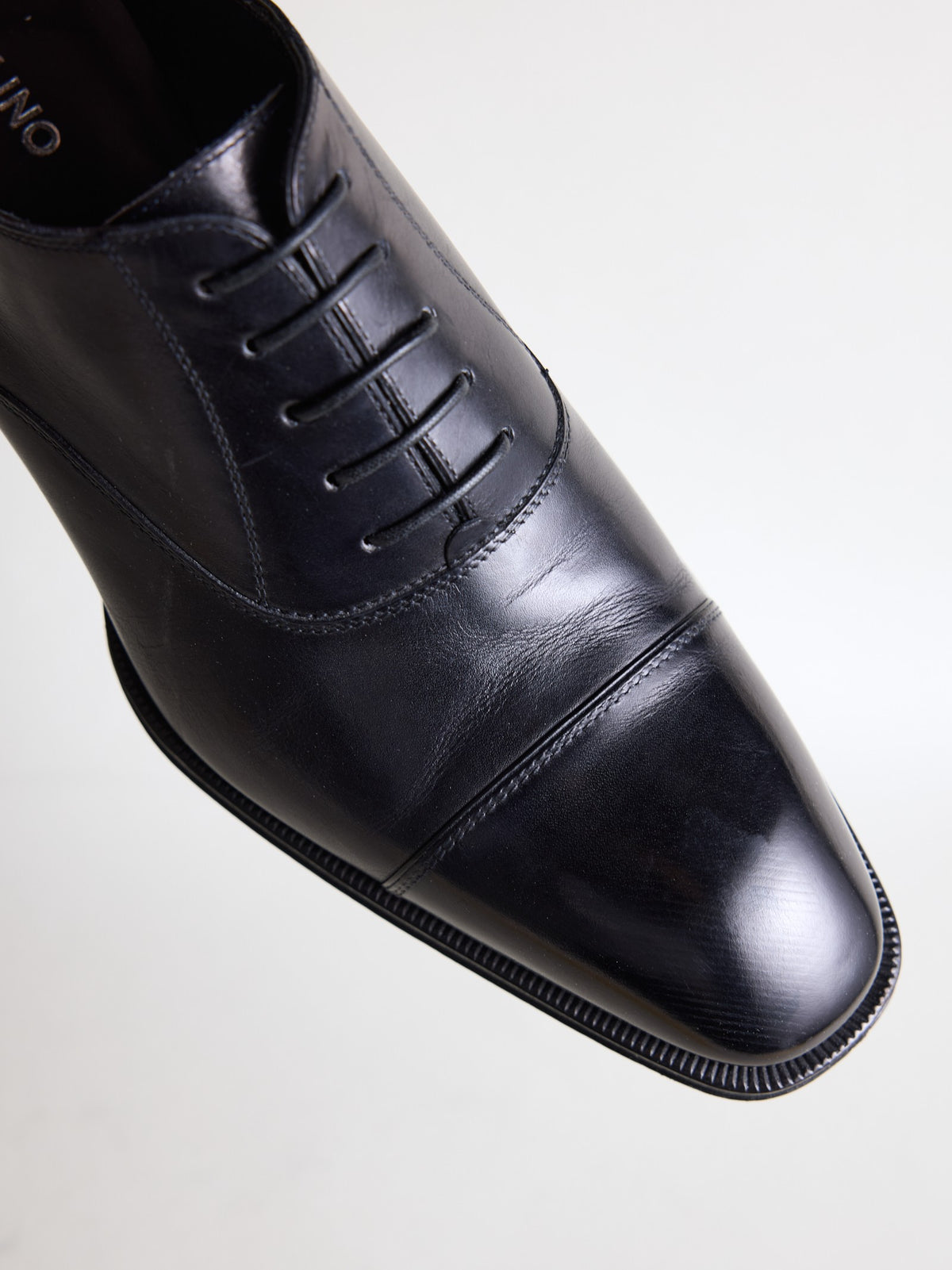 Close-up of the polished cap toe and closed lacing on the black oxford