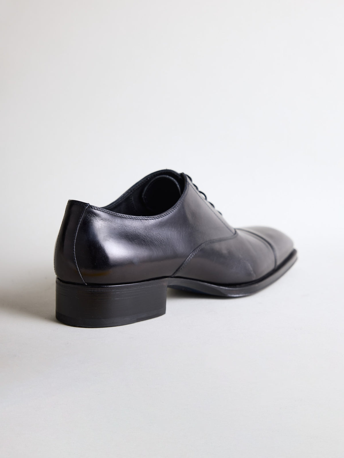 Black cap-toe oxford shoe from a rear angle showing the 3.5 cm heel